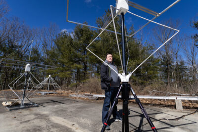 A man standing outside next to a tall antenna