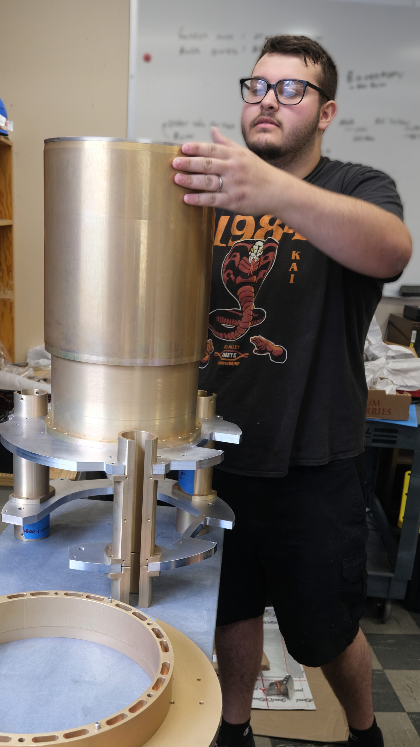 a man assembling a large, gold-colored metal tube